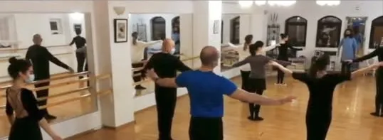 Adulți la bara de balet, cu profesorul în fața oglinzii