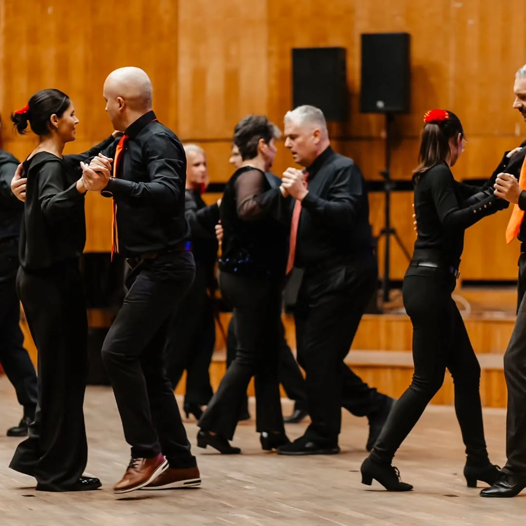 Grupă de adulți dansând în pereche pe scenă, la Timisoara Dance Studio