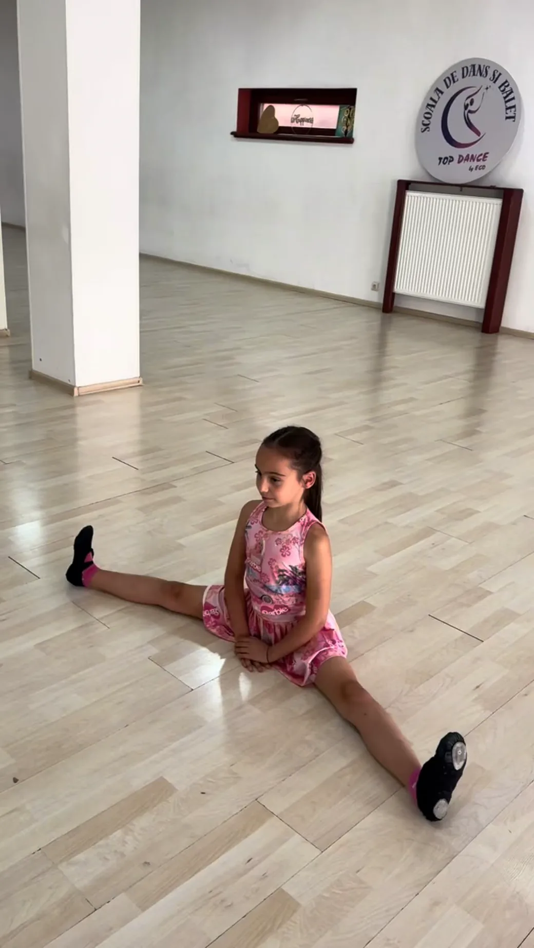 Copilă la antrenamentul de dans sportiv, în sala Top Dance din Timișoara, cu sigla școlii pe perete
